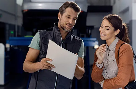 Ein Mann und eine Frau betrachten gemeinsam ein Dokument in einer modernen Werkstatt oder Büroumgebung und lächeln dabei.
