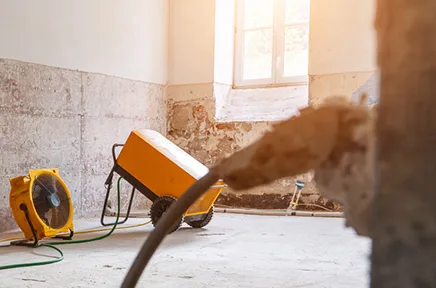 Orangefarbenen Bautrockner in einem Rohbau-Raum mit Betonwänden