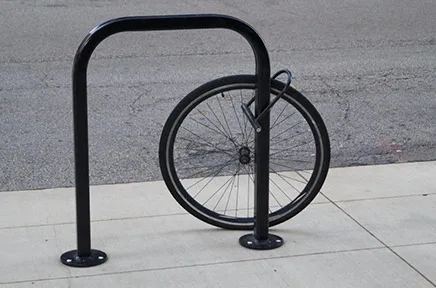 Ein einzelnes Fahrradrad ist an einem schwarzen Fahrradbügel auf einem Gehweg angeschlossen, der Rest des Fahrrads wurde offenbar gestohlen.